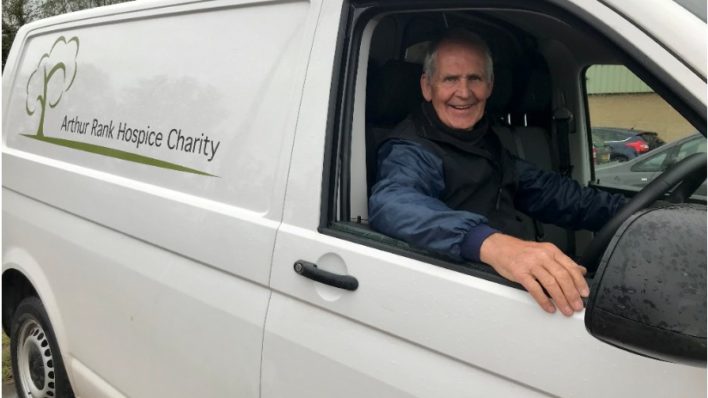 Male volunteer smiling in drivers seat of white transit van
