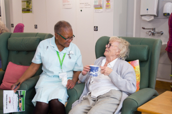 Female patient with a cup of tea, chats to healthcare assistant in the Evelyn Living Well Centre at Arthur Rank Hospice Charity