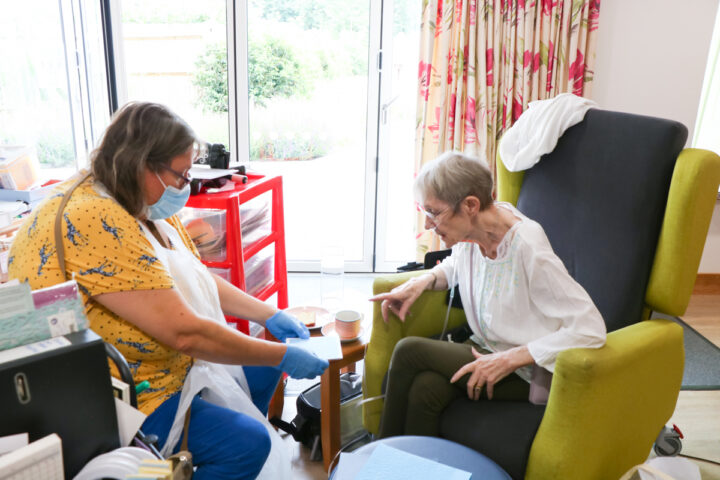 Faith help Laine, a patient attending our Living Well Service, choses the card she wants to use in a creative project