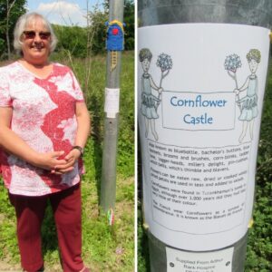 Lady smiling with a red top and trousers standing next to a blue painted door on the lampost leading to Arthur Rank Hospice