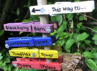 Painted pegs with door names pointing to the Fairy Doors leading to Arthur Rank Hospice
