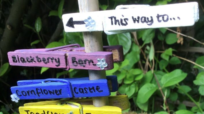 Painted pegs with door names pointing to the Fairy Doors leading to Arthur Rank Hospice