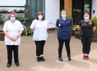 Colleagues from the Hospice at Home team standing outside of the Hospice. They are wearing their uniform and face coverings.
