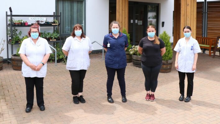 Colleagues from the Hospice at Home team standing outside of the Hospice. They are wearing their uniform and face coverings.
