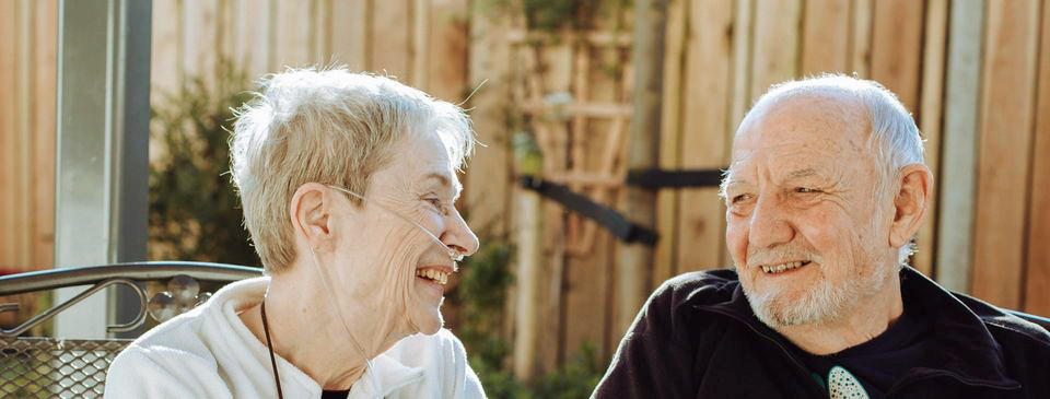 Laine and Geoff laughing together in the gardens at the Hospice