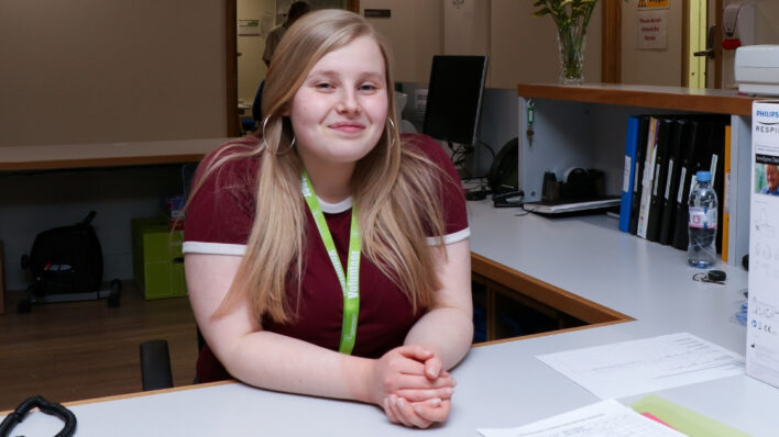 volunteer young woman sat on reception desk smiling