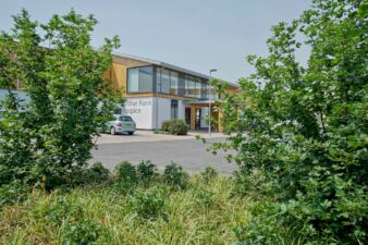 Arthur Rank Hospice taken behind bushes which frame the front of the Hospice
