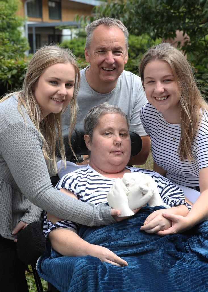 Family in Hospice garden with their mum, holding their hand cast