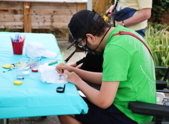 Young man in bright green tshirt concentrates on illustrating a white cotton cap