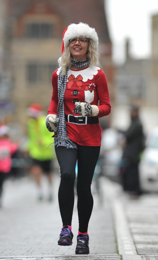 Female adult dressed in red and white running along the pavement