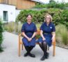 Two smiling female nurses sitting on a bench in the garden