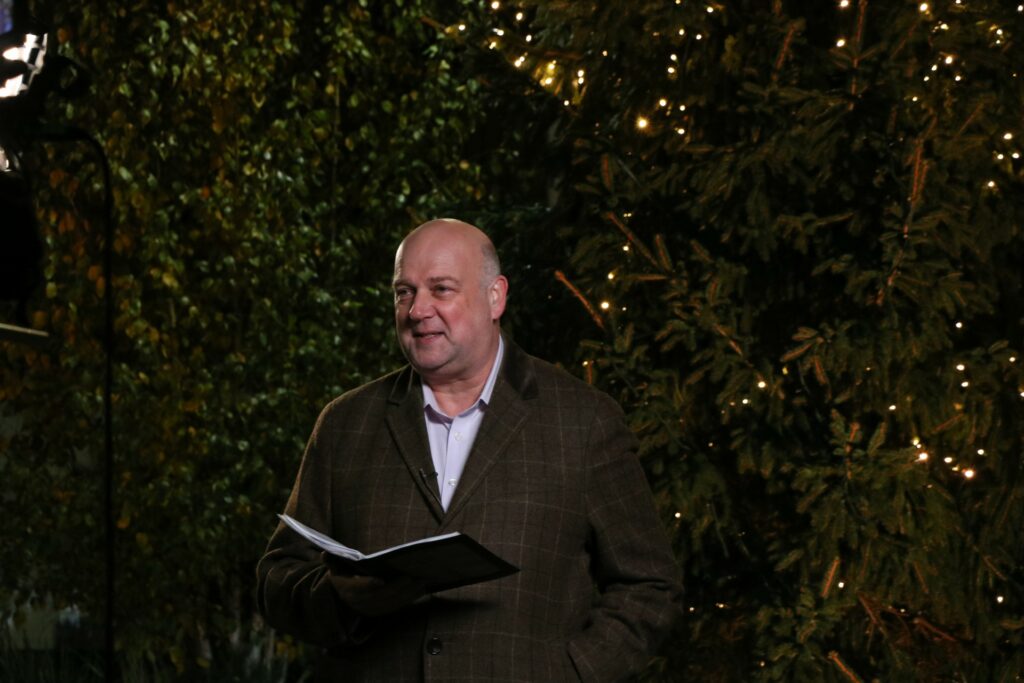 Male holding a book standing in front of a Christmas tree at night