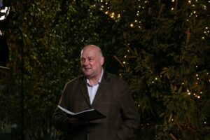 Male holding a book standing in front of a Christmas tree at night