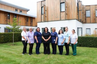 Eight members of the Inpatient Unit team, each wearing a different uniforms in the garden