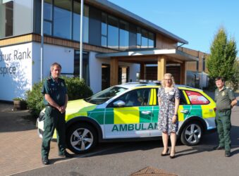 Director of Clinical Services, Sara Robins with members two members of EAAST and an ambulance car outside Arthur Rank Hospice Charity's Shelford based home