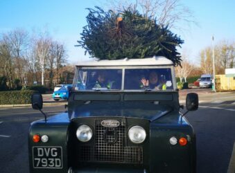 Green Landrover van with a Christmas Tree on the roof