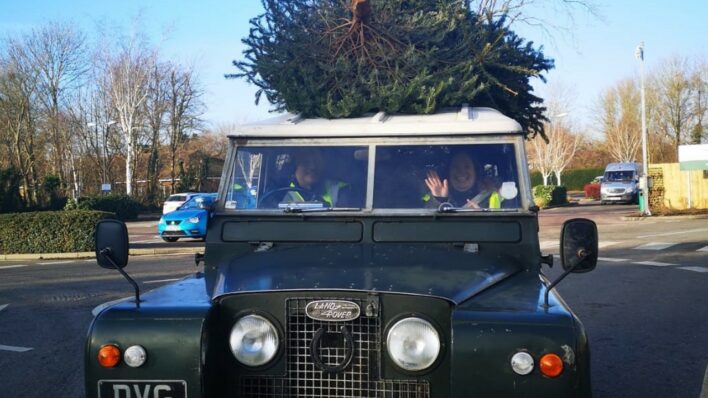 Green Landrover van with a Christmas Tree on the roof