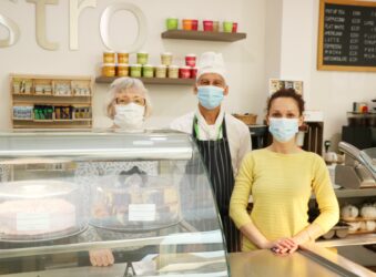 2 females and 1 male wearing masks standing behind Bistro counter