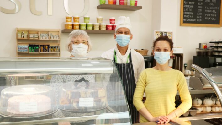 2 females and 1 male wearing masks standing behind Bistro counter