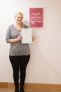 Female holds certificate standing in front of Charity values