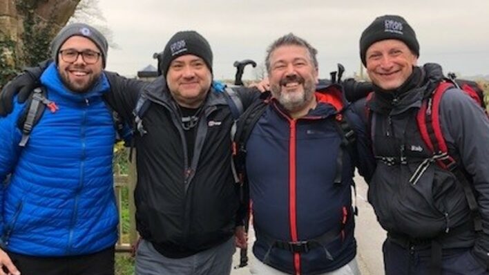 4 males with arms around each other, dressed for a walking challenge