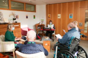 Three people taking part in a music therapy session sing along to the keyboard