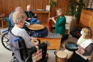 Three patients play various instruments as part of Music Therapy session in the Hospice's Sanctuary