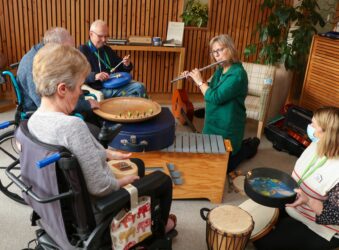 Three patients play various instruments as part of Music Therapy session in the Hospice's Sanctuary