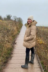 Female smiling at camera wearing beige hat and coat outside