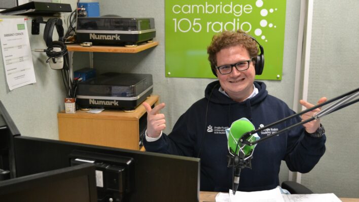 Male smiling at the Cambridge with Cambridge 105 in the background