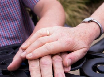 Woman's hand placed on top of a man's, in garden area