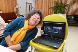 Female smiling next to a laptop and female on screen 