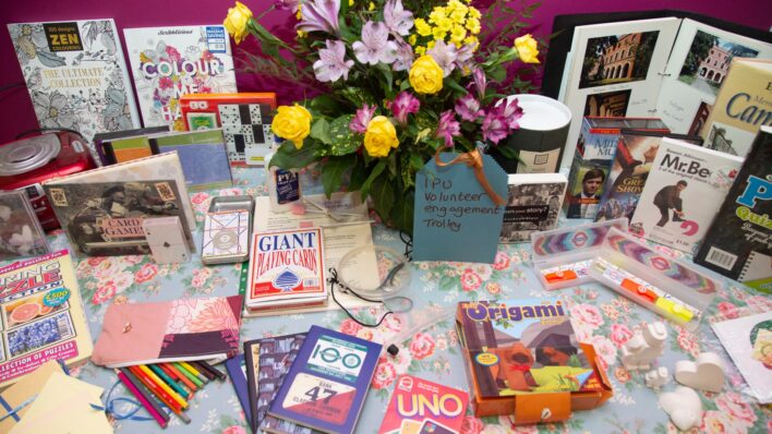 Books, games, flowers displayed on a blue table cloth