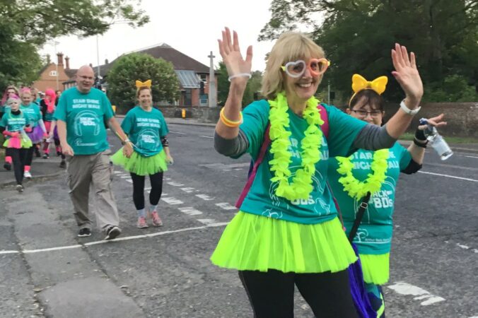 Star Shine Night Walk participants walking across a road. Two participants at the front wave at the camera.