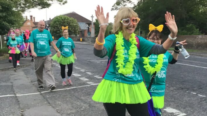 Star Shine Night Walk participants walking across a road. Two participants at the front wave at the camera.