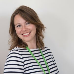 Female smiling at camera wearing a black and white striped top and green lanyard 