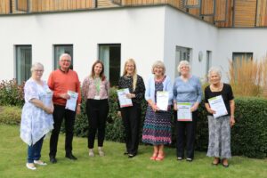 Males and females in the Hospice garden proudly holding their Long Service award certificate