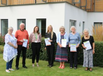 Males and females in the Hospice garden proudly holding their Long Service award certificate