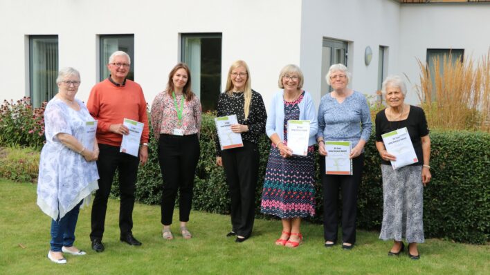 Males and females in the Hospice garden proudly holding their Long Service award certificate