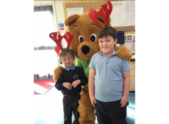 Life sized bear and 2 mboys in school uniform wearing red antlers