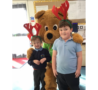 Life sized bear and 2 mboys in school uniform wearing red antlers