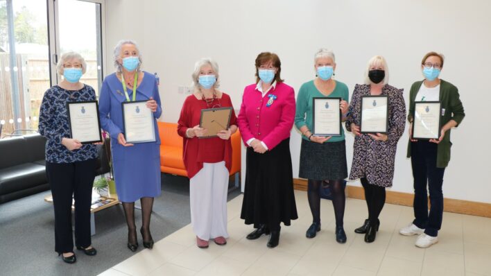 7 females weraing a mask holding awards