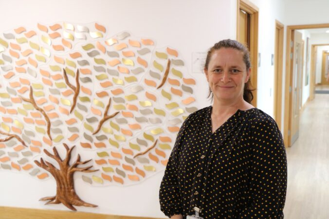 Female wearing black dress standing in front of memory tree