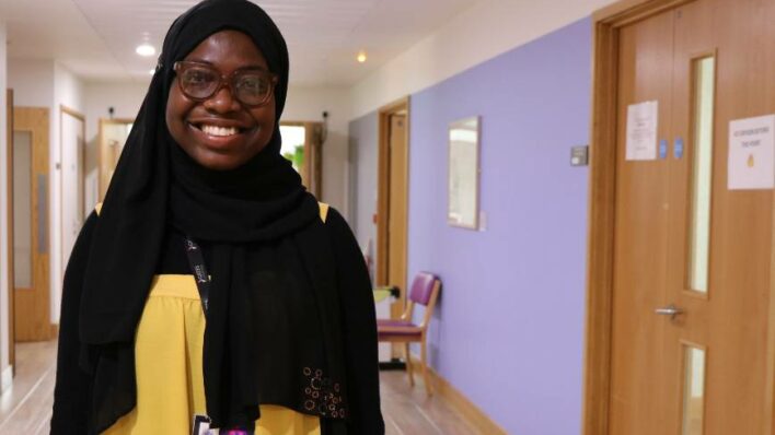 female volunteer in headscarf and yellow top smiling in corridor