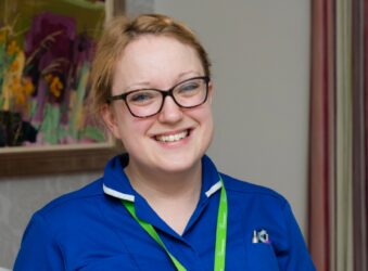 Female with blue nurse uniform smiling at the camera