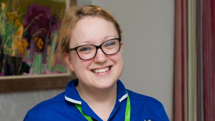 Female with blue nurse uniform smiling at the camera