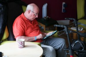 Male sitting in a chair looking at an ipad 