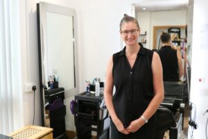Female wearing glasses and black top smiling at camera