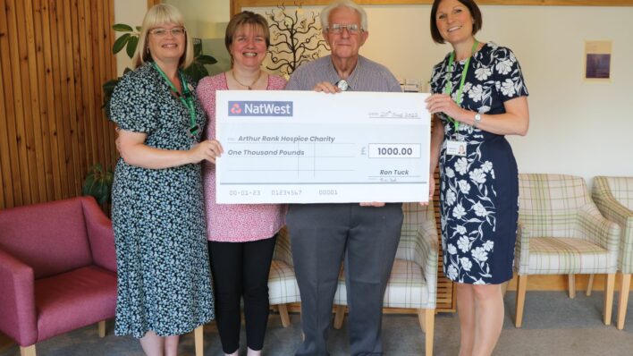 Four people holding a cheque