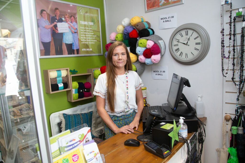 Female standing behind a till looking at the camera